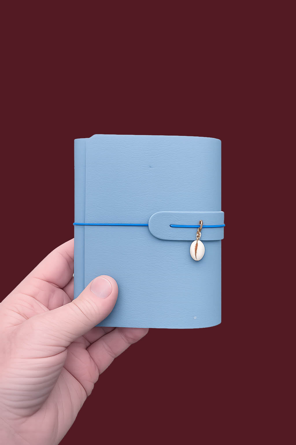 Hand holding a light blue notebook with a gold zipper on a dark red background